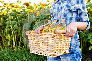 Basket with three bottles of sunflower oil in hands of girl