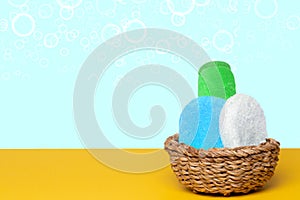 Basket with three colorful terry towels or cosmetic for body care on a yellow table over blue background with copy space. For your