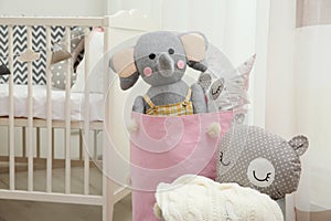 Basket with toys near crib in baby room. Interior design