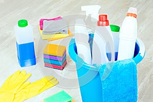 Basket with variety cleaning products on wooden floor. Housekeeping concept