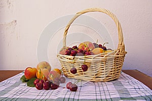 A basket with various types of fruits on a kitchen towel and blank rustic background