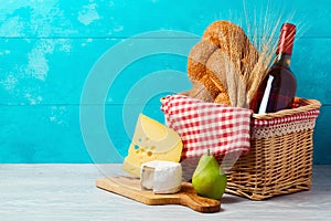 Basket with wine bottle, bread and cheese on wooden table. Jewish holiday Shavuot