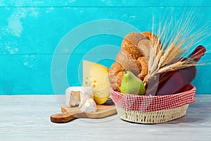 Basket with wine bottle, bread and cheese on wooden table. Jewish holiday Shavuot