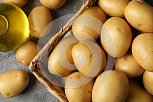 Basket with young potato on grey background