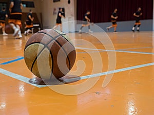 Basketball ball on court with free throw line, out of focus players in the background