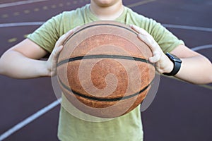 Basketball ball in the hands of a teenager, close up. Healthy lifestyle and sport concepts