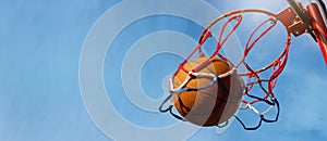 Basketball ball scoring the points against blue sky background at outdoor streetball court. copy space