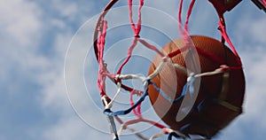 Basketball ball scoring the points against blue sky at outdoor streetball court