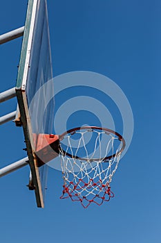 Basketball board and hoop with blue sky.