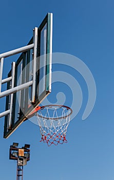 Basketball board and hoop with blue sky background.