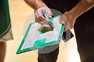 Basketball coach holds a clipboard and with a marker explain the tactic of the game to a player. photo