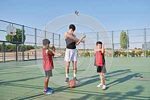 Basketball coach doing arm stretching exercises with two children, one of them has a leg prosthesis