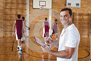Basketball coach holding clipboard in the court