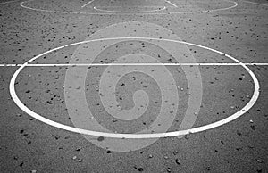 Basketball court in autumn with fallen leaves on it. Black and white