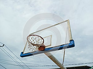 Basketball hoop against the background of the sky with clouds.