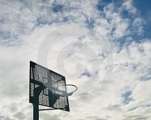 Basketball hoop against dramatic backlight sky background.