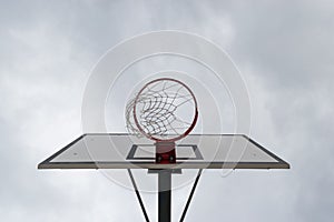 Basketball hoop, basket against white cloudy sky. Outside, street basketball court.