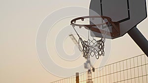 Basketball hoop close up at sunset and scored ball