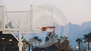 Basketball hoop net flutters in the wind at sunset