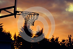 Basketball hoop silhouette against a bright sunset