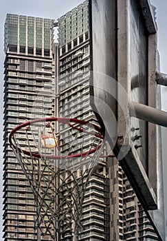 Basketball hoop and white net on Basketball backboard and street lamp against modern condo building background