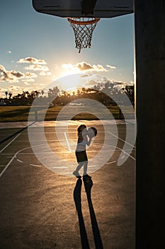 Basketball kids training game on silhouette sunset.