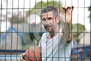 Basketball player in activewear leaning against fence court