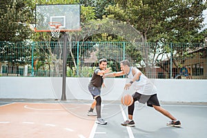 a basketball player carrying the ball is blocked by his opponent's players