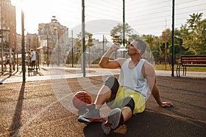 Basketball player drinks water on outdoor court