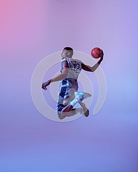 Basketball player jumping with ball in studio