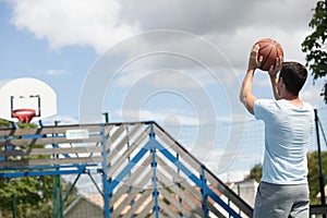 Basketball player makes throw on outdoor court