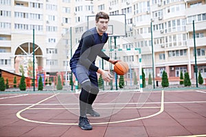 Basketball player in the open stadium trains, runs with a ball.