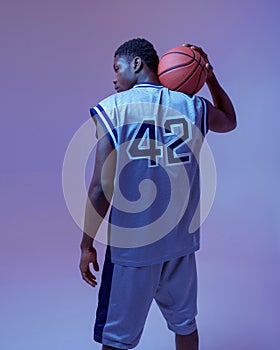 Basketball player poses with ball, back view