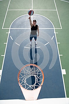 Basketball player shooting ball in hoop outdoor court. Urban youth game. Concept of sport success, scoring points and