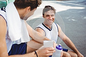 Basketball player showing mobile phone to friend