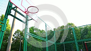 Basketball player trains playing basketball in the open air. A young man trains jumping with a basketball to hit the