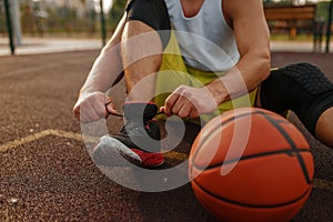 Basketball player tying laces on outdoor court