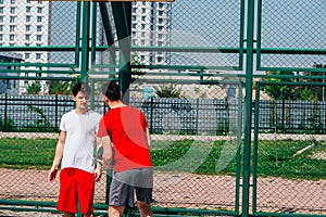 Basketball players playing ball pushing, dribbling on an urban basketball ground while the white skyscrapers nearly touch the