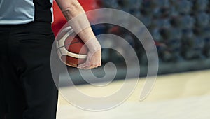 Basketball referee with ball on sport hall background