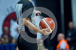 Basketball referee holding a basketball at a game in a crowded sports arena