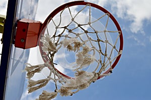 Basketball ring close-up from below wind swaying mesh against blue sky