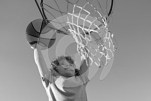 Basketball Slam Dunks of sporty kids basketball player. Close up image of basketball excited kid player dunking the ball