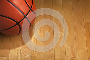 Basketball with spot lighting on wood gym floor