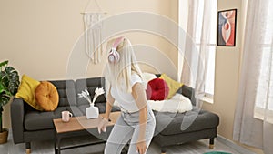 Basking in joy, young blonde woman grooving to music while relaxing indoors