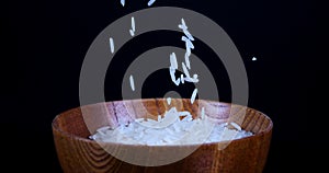 Basmati white rice falling in wooden bowl on a black spinning background