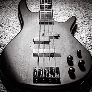 Bass electric guitar with four strings in black and white. Popular rock musical instrument. Top view of bass guitar, focus on photo