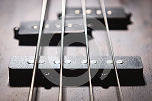 Bass electric guitar with four strings closeup. Detail of popular rock musical instrument. Close view of element of wooden