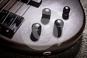 Bass electric guitar with four strings closeup. Detail of popular rock musical instrument. Close view of elements of wooden