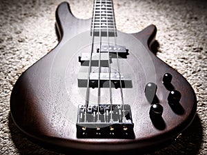 Bass electric guitar with four strings closeup. Popular rock musical instrument. Close view of brown guitar, focus on bridge photo