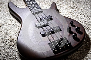 Bass electric guitar with four strings. Popular rock musical instrument. Close view of brown bass on carpet photo